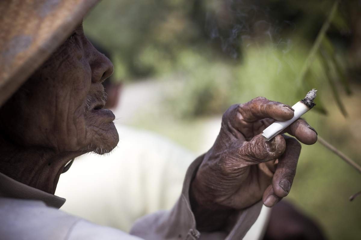 Mbah Sopawiro saat menikmati tembakau linting di pematang sawahnya di Bantul, Yogyakarta