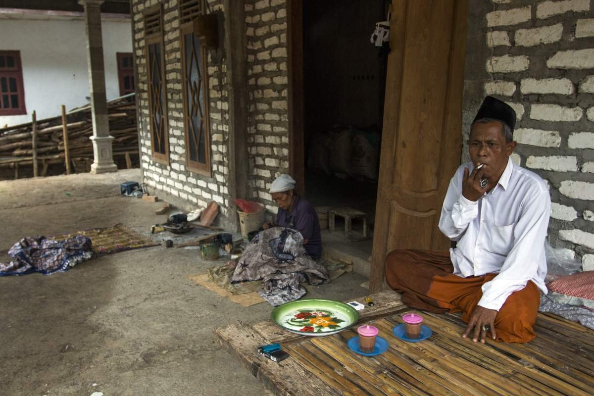 menikmati sebatang kretek di teras rumah