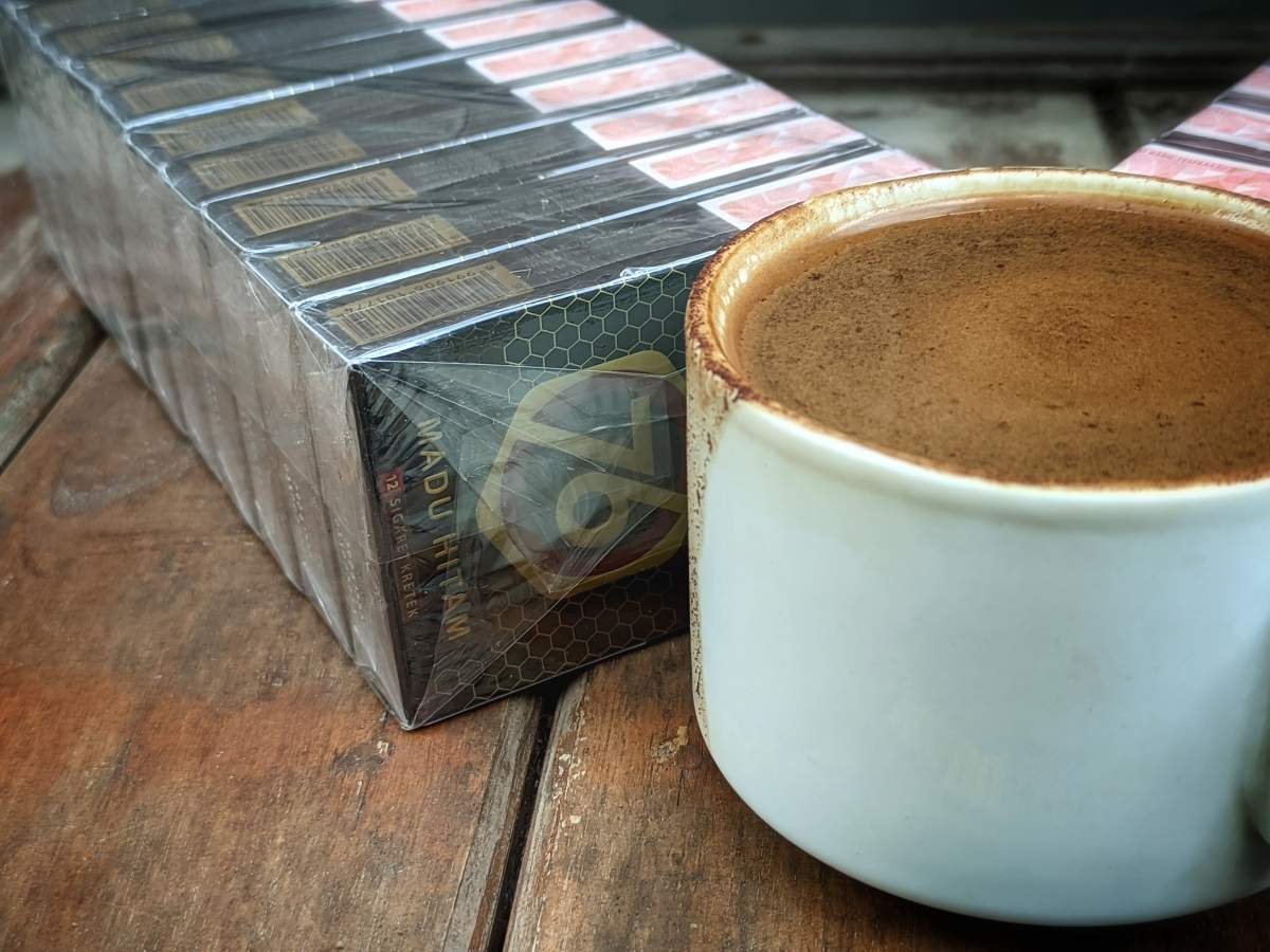 secangkir kopi dan satu slop djarum 76 madu hitam